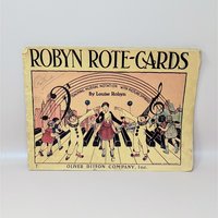 A vintage 1935 softcover music book titled Robyn Rote-Cards featuring a colorful illustration of children and clowns on a piano keyboard