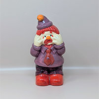 A vintage handpainted ceramic figurine of a crying clown wearing a purple suit and red tie with his hands to his face