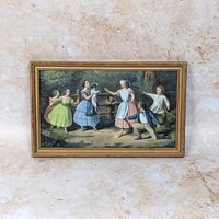 A vintage framed Currier and Ives print titled Blind Man's Buff on a tan textured background. The mid-century horizontal lithograph depicts Victorian-era children playing a blindfolded game in a lush green backyard space.