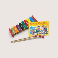 A vintage toy colorful melody xylophone with a songbook and two mallets, centered on a beige background.
