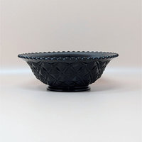 A vintage footed bowl in ebony black glass featuring a deep diamond block pressed pattern and a scalloped rim