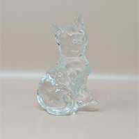 A vintage solid clear glass figurine of a sitting cat with pointed ears and a curled tail