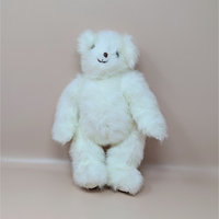 A vintage white jointed teddy bear by artist Joan Chesney with fluffy fur and a hand stitched smile