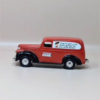 A red and black die cast metal 1946 Chevy Suburban van replica in its original box. The side of the van features the Hardware Hank logo and a cartoon mascot with a slogan.