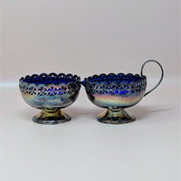 A vintage silverplated cream and sugar set with vibrant cobalt blue glass liners. The silver housings feature intricate pierced celtic knot patterns and footed bases.