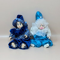 A pair of vintage porcelain baby clown dolls in shades of blue. One wears a dark blue velvet leopard print suit, and the other wears a bright blue satin suit with a white fuzzy wig and ruff collar.
