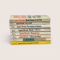 A stack of eight vintage Agatha Christie paperback books showing their colorful spines, centered on a beige background.
