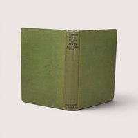 A vintage green cloth hardcover book spine and boards standing upright against a neutral backdrop