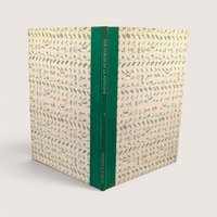 A vintage hardcover book standing upright showing a green cloth spine and patterned cream and green boards