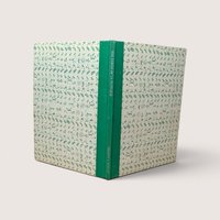 A vintage hardcover book standing upright showing a green cloth spine and patterned cream and green boards