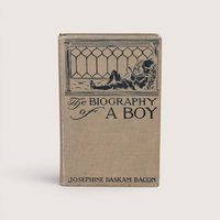 An antique beige cloth hardcover book with a dark green illustration of a boy lounging and reading