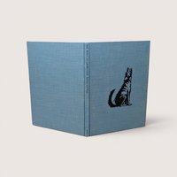 A vintage blue cloth hardcover book standing upright showing a black stamped illustration of a howling wolf on the front cover
