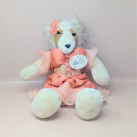 A vintage 1985 North American Bear Co plush doll named Collie Parton. She is a white and tan collie dog dressed in a voluminous peach satin stage dress with a lace-up bodice and a matching hair bow.