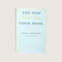 Vintage cookbook titled The New World Wide Cook Book by Pearl V Metzelthin centered on a plain linen background.