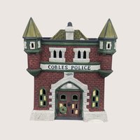 Dept. 56 Cobles Police Station ceramic building with a red brick facade and twin green turrets on a plain background.