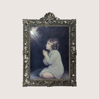 A vintage heavy ornate brass frame holding Sir Joshua Reynolds painting of The Infant Samuel behind curved bubble glass.
