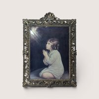 A vintage heavy ornate brass frame holding Sir Joshua Reynolds painting of The Infant Samuel behind curved bubble glass.