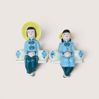 Pair of ceramic Asian-inspired shelf sitter figurines wearing light blue and teal attire, centered on a plain linen background.