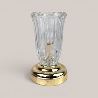 Clear glass tulip chimney lamp with a brass base on a plain background.