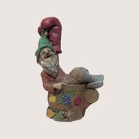 1993 Tom Clark signed Punch gnome figurine inside a fruit bowl wearing a large red boxing glove on a linen background