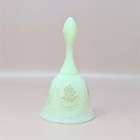 A vintage Fenton custard satin glass bell featuring a hand-painted pink floral spray, signed by artist S. Johnson, set against a neutral background.