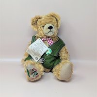 A vintage Hermann limited edition mohair teddy bear wearing a green traditional Bavarian vest and red checkered bow tie.