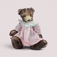 Vintage handmade mohair artist teddy bear by Debra Bistodeau wearing a pink dress with lace trim.