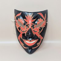 A vintage handmade paper mache wall mask featuring a black base with hand-painted red floral patterns and gold outlines