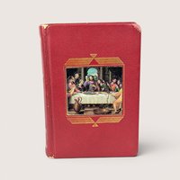 A vintage red textured leatherette catholic missal book featuring a central full color inlay illustration of the last supper.