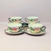 A vintage set of four Franciscan Desert Rose tea cups and saucers featuring hand-painted pink wild roses and green leaves on a cream ceramic base.