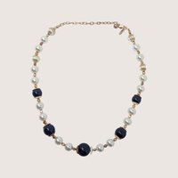 Vintage George statement necklace with dark blue glass beads, white pearls, and gold accents on a linen background