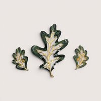Vintage Sarah Coventry Enchanted Forest green enamel oak leaf brooch and clip on earrings set on a linen background