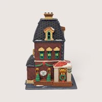 A handpainted porcelain Dept 56 Haberdashery metropolitan building on a linen background
