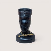 Hand-carved vintage black wooden bust of a figure from Ghana wearing a tall headdress and a rustic twine necklace.