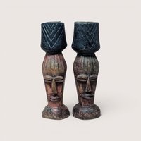 Pair of vintage hand-carved dark wood candlestick holders shaped like stylized African faces with geometric chevron cups.