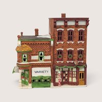 A handpainted porcelain Dept 56 Variety Store and Barber Shop building on a linen background