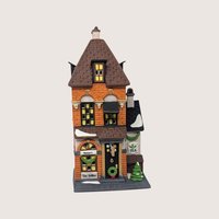 A handpainted porcelain Dept 56 Potters Tea Seller building on a linen background