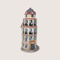 A handpainted porcelain Dept 56 The Tower Cafe flatiron style building on a linen background