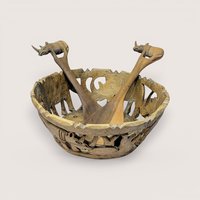 Hand carved wooden bowl with openwork safari animal designs alongside two matching rhinoceros topped serving utensils.