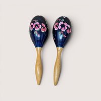 Pair of vintage handpainted dark blue wooden maracas with pink floral motifs and light wood handles.