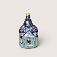 Hand painted iridescent glass Christopher Radko Christmas ornament shaped like a church with glittery purple roofs.