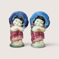 Two vintage Royal Copley ceramic planters shaped like a cheerful child in a large blue bonnet.
