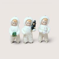 Three Department 56 Snow Angel figurines standing side by side in textured white snowsuits on a plain background