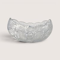 An oval clear cut glass bowl with sharp geometric starburst patterns and a sawtooth rim on a plain background