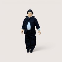 A vintage Oliver Hardy jointed action figure wearing a black suit and bowler hat standing on a plain background