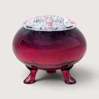 A vintage ruby red glass footed flowerite bowl sitting on three scrolled feet with a clear glass flower frog insert.A vintage ruby red glass footed flowerite bowl sitting on three scrolled feet with a clear glass flower frog insert.