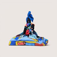 Vintage handmade cloth Caribbean folk art doll wearing a colorful patterned skirt and a bright blue head wrap.A vintage handmade Black cloth folk art doll wearing a vibrant, colorful abstract dress and a matching blue headwrap.