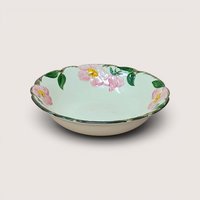 A vintage hand painted ceramic bowl featuring pink roses and green leaves on a cream background with a sculpted edge.