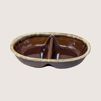 A vintage oval divided ceramic casserole dish with a glossy brown drip glaze trim on a plain background