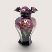 A dark purple aubergine glass vase with a ruffled rim and hand painted purple flower on a light beige backdrop